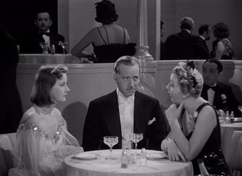 Movie still from “Ninotchka” (1939), directed by Ernst Lubitsch – A group of people sitting at a table with wine glasses on it; Medium shot, High angle