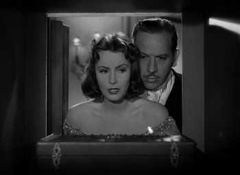 Movie still from “Ninotchka” (1939), directed by Ernst Lubitsch – A man and a woman standing next to each other in front of a suitcase; Medium shot, Over the shoulder angle