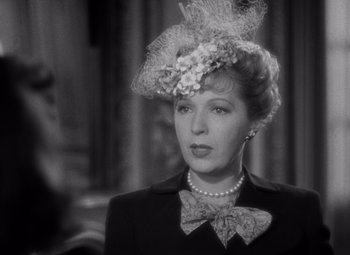 Movie still from “Ninotchka” (1939), directed by Ernst Lubitsch – An old photo of a woman wearing a hat and a bow tie; Close Up shot, Over the shoulder angle