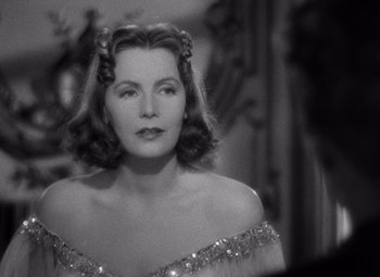 Movie still from “Ninotchka” (1939), directed by Ernst Lubitsch – A black and white photo of a woman in a dress; Close Up shot, Over the shoulder angle
