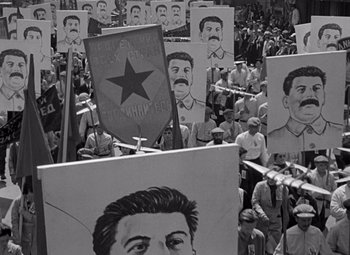 Movie still from “Ninotchka” (1939), directed by Ernst Lubitsch – A black and white photo of a crowd of people holding signs; Medium shot, High angle