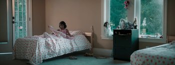 Movie still from “Nishabdham” (2020), directed by Anunagaveera – A little girl sitting on a bed looking out a window; Wide shot, High angle