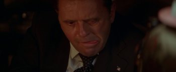 Movie still from “Nixon” (1995), directed by Oliver Stone – A person wearing a suit and tie; Extreme Close Up shot, Low angle
