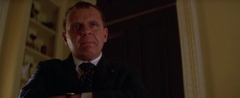 Movie still from “Nixon” (1995), directed by Oliver Stone – A person wearing a suit and tie; Close Up shot, Low angle