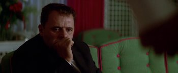 Movie still from “Nixon” (1995), directed by Oliver Stone – A man sitting in a chair with his hand on his chin; Close Up shot, Low angle