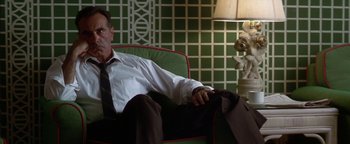 Movie still from “Nixon” (1995), directed by Oliver Stone – A man sitting in a chair in front of a lamp; Medium shot, Low angle