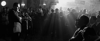 Movie still from “Nixon” (1995), directed by Oliver Stone – A group of people standing in front of a crowd; Medium shot, Low angle