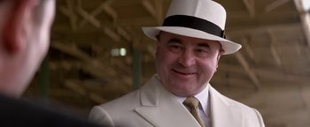 Movie still from “Nixon” (1995), directed by Oliver Stone – A person wearing a suit and a hat; Close Up shot, Over the shoulder angle