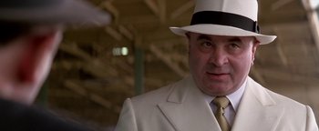 Movie still from “Nixon” (1995), directed by Oliver Stone – A man in a white suit and a white hat; Close Up shot, Low angle