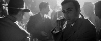 Movie still from “Nixon” (1995), directed by Oliver Stone – A black and white photo of a man smoking a cigarette; Close Up shot, Low angle