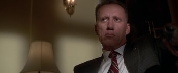 Movie still from “Nixon” (1995), directed by Oliver Stone – A person wearing a suit and tie; Close Up shot, Low angle