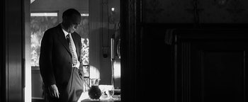 Movie still from “Nixon” (1995), directed by Oliver Stone – A woman standing in front of a mirror in a room; Medium shot, Low angle