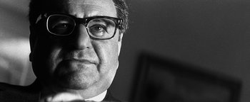 Movie still from “Nixon” (1995), directed by Oliver Stone – Black and white photograph of a man wearing glasses; Close Up shot, Low angle