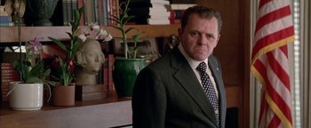 Movie still from “Nixon” (1995), directed by Oliver Stone – A person wearing a suit and tie; Close Up shot, Low angle