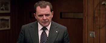 Movie still from “Nixon” (1995), directed by Oliver Stone – A person wearing a suit and tie; Close Up shot, Low angle