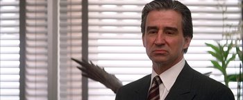 Movie still from “Nixon” (1995), directed by Oliver Stone – A man in a suit and tie with an arrow behind him; Close Up shot, Low angle