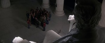 Movie still from “Nixon” (1995), directed by Oliver Stone – A group of people standing in front of a statue; Extreme Wide shot, High angle