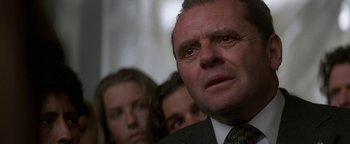 Movie still from “Nixon” (1995), directed by Oliver Stone – A person wearing a suit and a tie; Close Up shot, Low angle