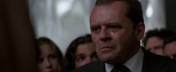 Movie still from “Nixon” (1995), directed by Oliver Stone – A man in a suit and tie looking at the camera; Close Up shot, Low angle