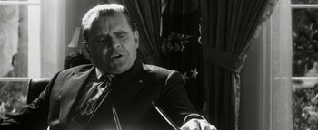 Movie still from “Nixon” (1995), directed by Oliver Stone – A black and white photo of a man in a suit and tie; Close Up shot, Low angle