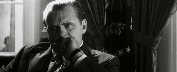 Movie still from “Nixon” (1995), directed by Oliver Stone – A black and white photo of a man in a suit and tie; Close Up shot, Low angle