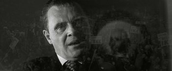 Movie still from “Nixon” (1995), directed by Oliver Stone – An older man wearing a suit and tie; Close Up shot, Low angle