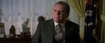 Movie still from “Nixon” (1995), directed by Oliver Stone – An older man in a suit and tie looking off into the distance; Close Up shot, Low angle