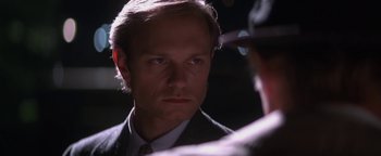 Movie still from “Nixon” (1995), directed by Oliver Stone – A person wearing a suit and tie; Close Up shot, Over the shoulder angle