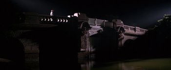 Movie still from “Nixon” (1995), directed by Oliver Stone – A person standing on a bridge at night; Extreme Wide shot, Low angle