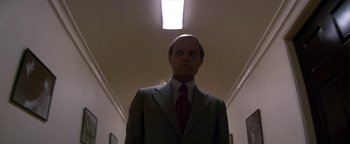 Movie still from “Nixon” (1995), directed by Oliver Stone – A man wearing a suit and tie standing in a hallway; Close Up shot, Low angle