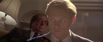 Movie still from “Nixon” (1995), directed by Oliver Stone – A man in a suit and tie standing next to another man in a suit and tie; Close Up shot, Low angle