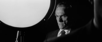 Movie still from “Nixon” (1995), directed by Oliver Stone – Black and white photograph of a man in a suit and tie; Close Up shot, Low angle