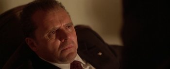 Movie still from “Nixon” (1995), directed by Oliver Stone – An older man in a suit and tie looking at the camera; Close Up shot, Low angle