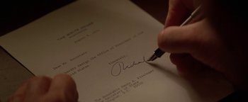 Movie still from “Nixon” (1995), directed by Oliver Stone – A person is signing a document with a pen; Extreme Close Up shot, High angle