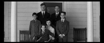 Movie still from “Nixon” (1995), directed by Oliver Stone – An old photo of a group of men and women; Medium shot, Low angle