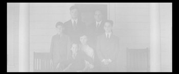 Movie still from “Nixon” (1995), directed by Oliver Stone – An old photo of a group of people in suits; Wide shot, Overhead angle