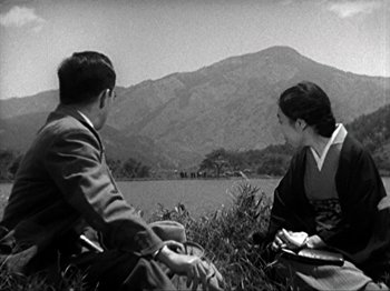 Movie still from “No Regrets for Our Youth” (1946), directed by Akira Kurosawa – A man and a woman sitting in a grassy field; Extreme Wide shot, High angle