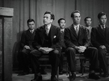 Movie still from “No Regrets for Our Youth” (1946), directed by Akira Kurosawa – A black and white photo of a group of men sitting on a bench; Medium shot, Low angle