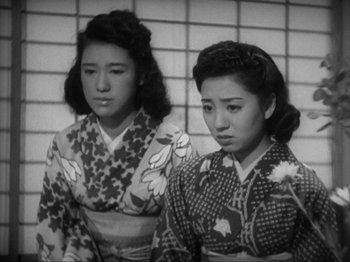 Movie still from “No Regrets for Our Youth” (1946), directed by Akira Kurosawa – Two young women in kimonos standing next to each other in front of a brick wall; Medium shot, Low angle