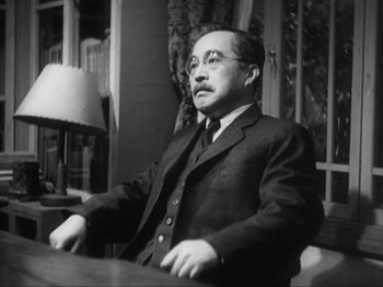 Movie still from “No Regrets for Our Youth” (1946), directed by Akira Kurosawa – An old black and white photo of a man sitting at a table; Close Up shot, Low angle