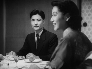 Movie still from “No Regrets for Our Youth” (1946), directed by Akira Kurosawa – An older man and woman sitting at a dinner table; Medium shot, Over the shoulder angle