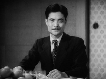 Movie still from “No Regrets for Our Youth” (1946), directed by Akira Kurosawa – A man in a suit sitting at a table with two glasses; Close Up shot, Low angle