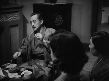 Movie still from “No Regrets for Our Youth” (1946), directed by Akira Kurosawa – An old photo of three people sitting at a table; Medium shot, Over the shoulder angle