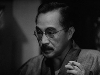 Movie still from “No Regrets for Our Youth” (1946), directed by Akira Kurosawa – An older man wearing glasses and holding a cigarette in his mouth; Close Up shot, Low angle