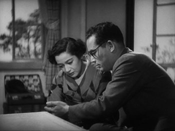 Movie still from “No Regrets for Our Youth” (1946), directed by Akira Kurosawa – An older man and a woman looking at something on a phone; Medium shot, High angle