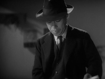 Movie still from “No Regrets for Our Youth” (1946), directed by Akira Kurosawa – A man wearing a suit and a hat is looking down; Medium shot, Low angle