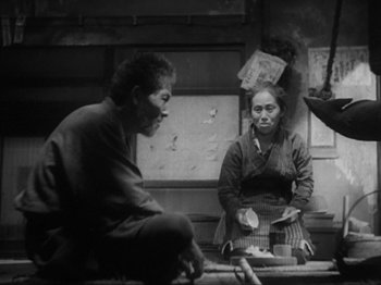 Movie still from “No Regrets for Our Youth” (1946), directed by Akira Kurosawa – A man and a woman sitting at a table in a kitchen; Medium shot, High angle