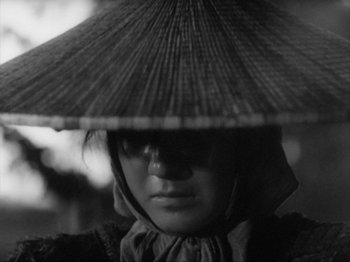 Movie still from “No Regrets for Our Youth” (1946), directed by Akira Kurosawa – A woman wearing a hat with an umbrella on top of her head; Close Up shot, High angle