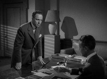 Movie still from “No Time for Love” (1943), directed by Mitchell Leisen – A man in a suit and tie standing in front of another man in a suit and tie in front of a desk; Medium shot, Over the shoulder angle