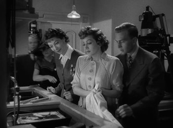 Movie still from “No Time for Love” (1943), directed by Mitchell Leisen – A black and white photo of a group of people in a room; Medium shot, Low angle